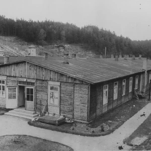 Zicht op een van de barakken met de wachttorens op de achtergrond