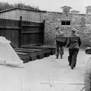 Doodskisten en kruisen worden van een wagen gelost in concentratiekamp Flossenbürg, Duitsland, voor de begrafenis van slachtoffers van Duitse gruweldaden die in het kamp zijn gevonden. Dit kamp stond onder toezicht van 800 nazi-SS-troepen en werd geopend in 1939. Volgens in het kamp gevonden documenten werden hier 54.890 mannen en meer dan 10.000 vrouwen gevangen gehouden. In de periode van 14 maanden voorafgaand aan 20 april 1945 stierven 14.000 gevangenen aan uitputting, ondervoeding, mishandeling en diverse ziekten. De gevangenen werkten in steengroeven en een nabijgelegen Messerschmidt-vliegtuigfabriek. Op 20 april 1945 werden 15.000 gevangenen, onder wie kinderen en ouderen, weggevoerd. Degenen die de mars niet konden bijhouden, werden vermoord. Ongeveer 2.000 mensen bleven achter in het kamp toen de Amerikaanse troepen arriveerden. Onder degenen die naar verluidt in het kamp gevangen hebben gezeten, bevinden zich Kurt von Schuschnigg, voormalig kanselier van Oostenrijk, Leopold, koning der Belgen, prins Albrecht van Beieren en Hjalmar Schacht, rijksminister van Financiën.