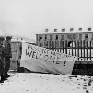 Twee soldaten van de 97ste Infanteriedivisie bekijken het bord bij de ingang van concentratiekamp Flossenbürg, Duitsland, waar wekelijks honderden Joodse, Franse, Russische en Slavische arbeiders stierven. Het kamp werd ontdekt door de 97ste Infanteriedivisie van het Amerikaanse 3de Leger.